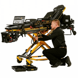 A man kneels beside a yellow medical stretcher, adjusting its controls with tools on the floor nearby.